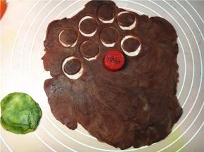 剩下的原色面团，加适量抹茶粉揉匀成绿色面团。红色面片，用小瓶盖按压成圆片。