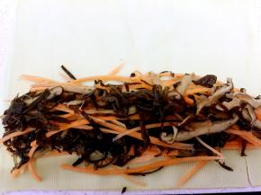 取一张铺开，在末端铺上胡萝卜丝、香菇丝、黑木耳丝