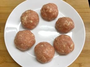 用勺子取一勺肉泥在手心中摔打再舀起反复五六次做成一个光滑的肉丸。
