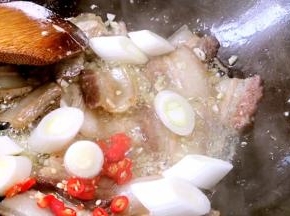 加入小米椒、大葱段炒香