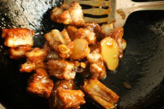 下入刚才煎好的排骨，快速翻炒，使焦糖全部裹在排骨上面，炒糖色做出来的排骨颜色特别好看。