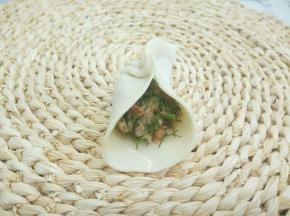 拿一张饺子皮，放上少许肉馅，饺子皮对捏