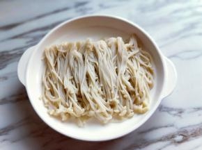焯水的金针菇捞出摆盘。