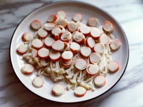 将切好的蟹肉棒片放在金针菇上面。