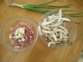 准备食材，猪肉洗干净切成丁，蟹味菇洗干净挤一下水。蒜头拍碎放到猪肉丁里。