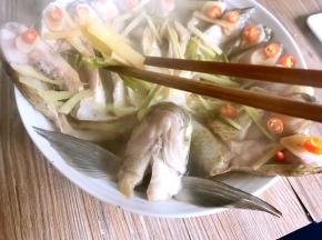 将蒸好的孔雀开屏鱼端出锅，将姜丝、葱段丢弃