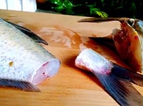 再将沥干水的鱼，直刀切下鱼头和鱼尾