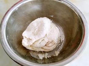 用手揉面，这个时候面团较硬，无法成型，盖上保鲜膜醒发10分钟。