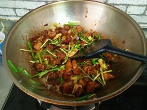 大火收汁，加入蒜苗段、芹菜段，翻炒均匀