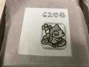 把打印好的镜像的旅行青蛙图案上放上一张油纸，用最深色的抹茶黄油霜勾勒出轮廓