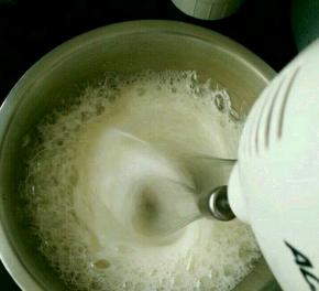 用打蛋器开始打发，白糖分三次加入。打到粗泡时加入三分之一白糖，继续打到泡沫细腻时加入第二次，再打到有明显纹路时加入剩下的白糖。