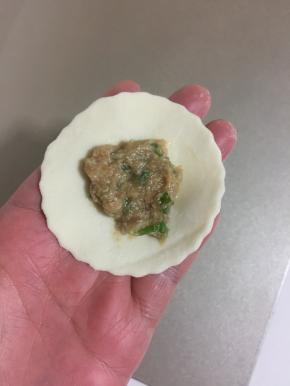 取一个饺子皮，在中间抹上适量的馅儿，按压一下。