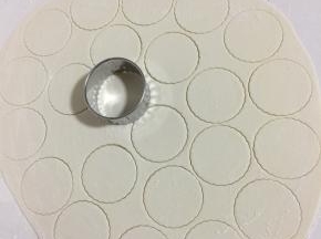 在面片上撒少许面粉防粘，用不锈钢饺子皮模具按压成一个一个的圆皮出来。