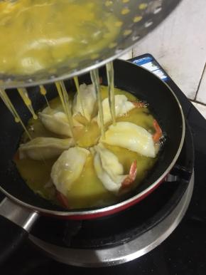 把蛋液通过漏勺均匀的倒在虾饺上。（没有漏勺，直接把蛋液倒进锅里也可。）