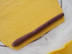 将红豆沙搓成条，放到面皮上裹起来。