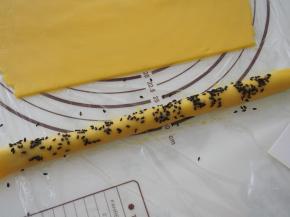 稍微揉一下，让豆沙和面皮贴合更紧密。刷上一层蛋液，撒上一层黑芝麻。