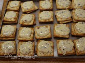 接着用勺子舀一些牛轧糖，倒在一块苏打饼干上面，再盖上另外一块饼干。