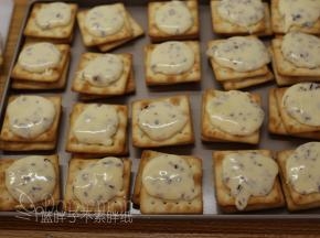 接着用勺子舀一些牛轧糖，倒在一块苏打饼干上面，再盖上另外一块饼干。