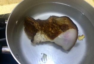 腊肉洗去表皮碳化物，锅里装入能淹没腊肉的水量，老姜切几片放入煮腊肉