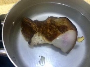 腊肉洗去表皮碳化物，锅里装入能淹没腊肉的水量，老姜切几片放入煮腊肉