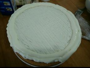 把一半混合好的酸奶倒在蛋糕上面，用刮板刮出纹路，然后剩下的酸奶装到裱花袋，剪去一个角，在蛋糕边边剂上两圈。(也可以不挤，问题不大)
