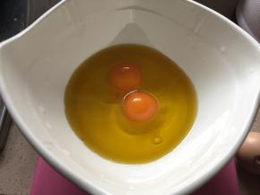 碗中磕入两颗鸡蛋、倒入食用油