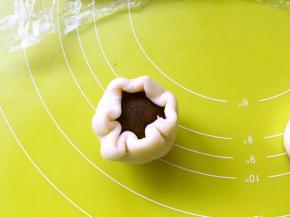 包裹上豆沙咸蛋黄，放手心用虎口一点点向上推面团，收好收口