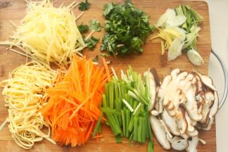 蒸饼的时候开始准备蔬菜。我准备了胡萝卜、豆腐皮、韭菜、香菇、土豆和绿豆芽，不仅好吃而且五颜六色。土豆去皮切成丝，胡萝卜切成丝，香菇切薄片，豆腐皮切成丝，韭菜切段，香菜茎和叶子分开切碎，葱姜切丝。