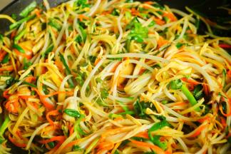 再根据蔬菜的易熟程度依次放入蔬菜炒熟。我这些蔬菜的顺序是胡萝卜、香菇、豆腐皮、豆芽、土豆丝、韭菜和香菜。最后加盐和五香粉调味，淋入少许芝麻油提香。