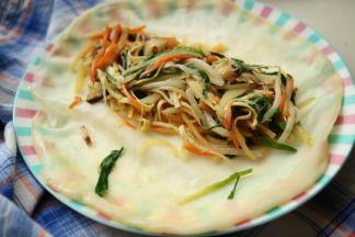 春饼铺在盘子里，放上刚才炒好的蔬菜，我喜欢多多的卷菜进去，这样才好吃。