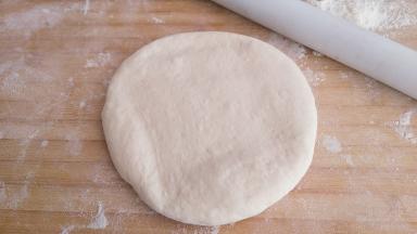 取一个剂子收圆，然后用擀面杖进行擀面。