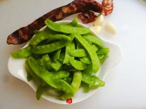 荷兰豆摘掉两头，洗干净备用。肠切片，蒜切沫。