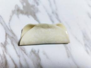 将饺子皮对折。