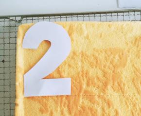 烤好的蛋糕片 倒扣放凉 平均分成两份。然后用纸画出一个你想要的数字 如果想要数字好看些 网上打印下来。我是直接自己画的 哈哈