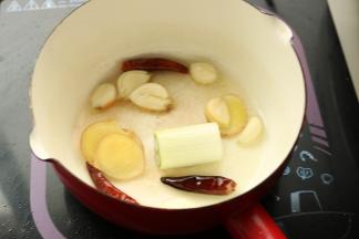 准备一个直径较小，锅深比较高的小锅，先放入少许油，爆香葱姜蒜和辣椒干，多炒一会，等香味都散发出来。