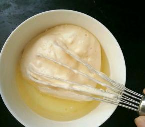 舀一勺蛋糕糊放到牛奶和玉米油的混合物里，搅拌均匀。