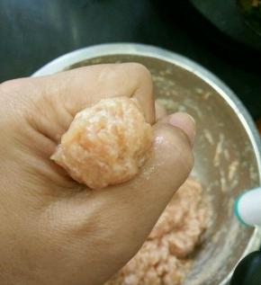 这时候可以放肉丸了，先用虎口轻轻挤出肉泥，再用不锈钢勺子把肉丸挑到锅里。