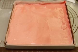 随意将两份蛋糕糊倒入方形烤盘内，表面刮平，轻震去气泡