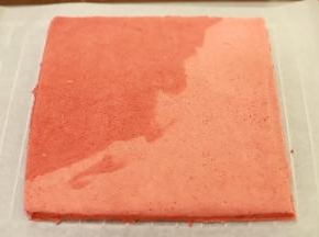 蛋糕片出炉后盖上油纸，倒扣放至温热，将蛋糕片边缘切整齐