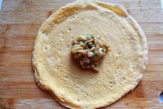 取一张蛋饼光面朝外，放入适量肉馅
