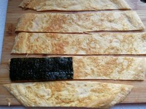 摊好的鸡蛋饼取出光面朝下，用刀分切成与海苔同宽的条状