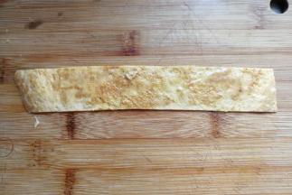 取一条鸡蛋饼先抹上少许生蛋液（无需再打鸡蛋液，摊饼时碗上的残留蛋液就够用哈）