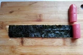 然后把台味香肠切成与海苔同宽的小段，摆在海苔上