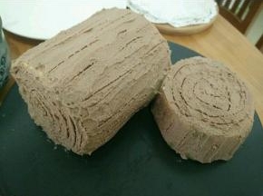 把定型好的蛋糕卷拿出来切成两块，用勺子把奶油抹上去，再用牙签画出纹路，随意画就好。