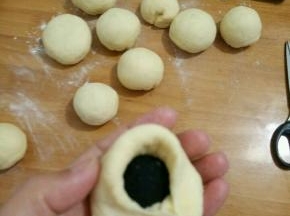 取个剂子擀开，放上适量芝麻馅，包好再搓圆。