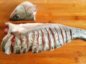 切去鱼头，用刀从鱼背往鱼腹切， 注意鱼腹不要切断，鱼尾影响开屏美观，也可以直接切掉