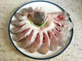 腌好的鱼放盘子摆出孔雀的造型，鱼头竖在中间，鱼尾塞在鱼头里面