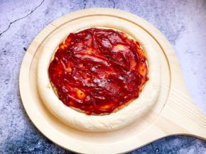 将3勺秘制番茄酱均匀的涂在披萨饼上。