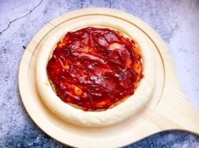 将3勺秘制番茄酱均匀的涂在披萨饼上。