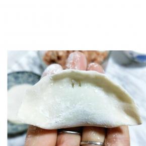 将饺子皮对折，再将两边捏紧。